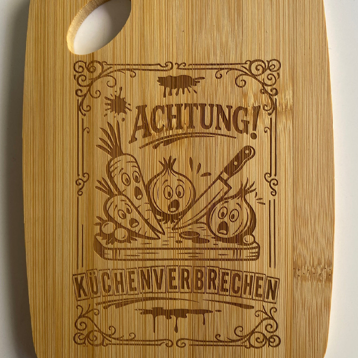 Lustiges Frühstücksbrettchen aus Bambus mit dem gravierten Spruch: „Achtung Küchenverbrechen“ als originelle Geschenkidee.