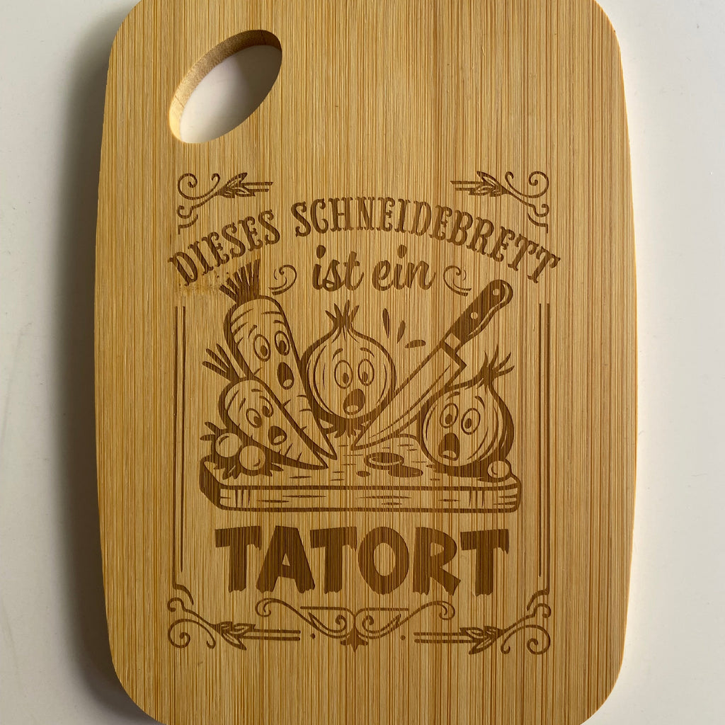 Graviertes Bambus-Schneidebrett mit dem humorvollen Text: „Dieses Schneidebrett ist ein Tatort“ für Hobbyköche.